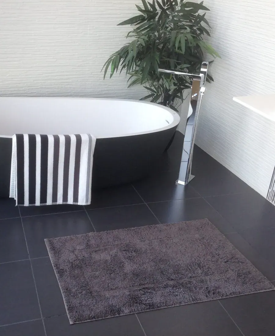 Kamar mandi dengan bak rendam dan tanaman di dekat jendela
